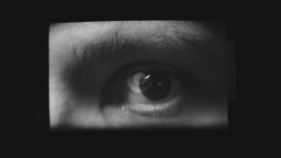 Film still from 'Viewfinder' (2025) by Jon Beaton. An eye in black-and-white as seen through a camera viewfinder.
